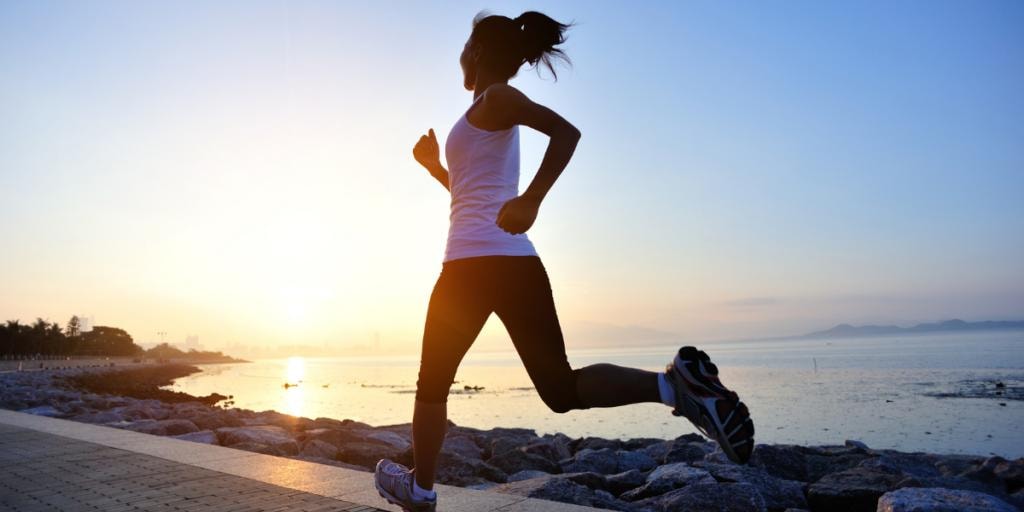 Woman jogging at sunrise by the water