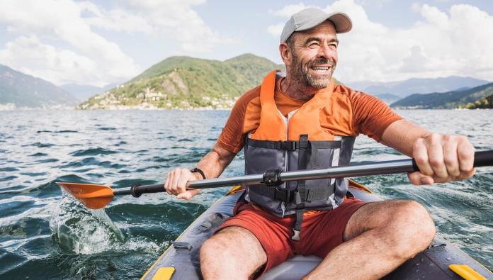 Man kayaking on a lake with mountains in the background